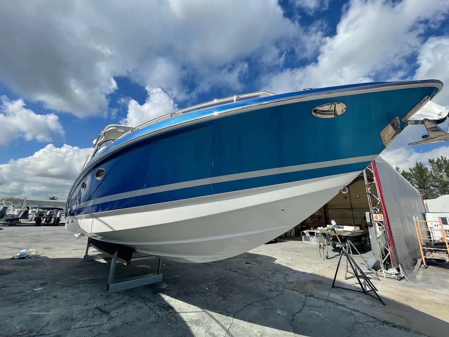 Bow of a powerboat with a mirror-gloss blue and white hull finish in a dry-dock setting