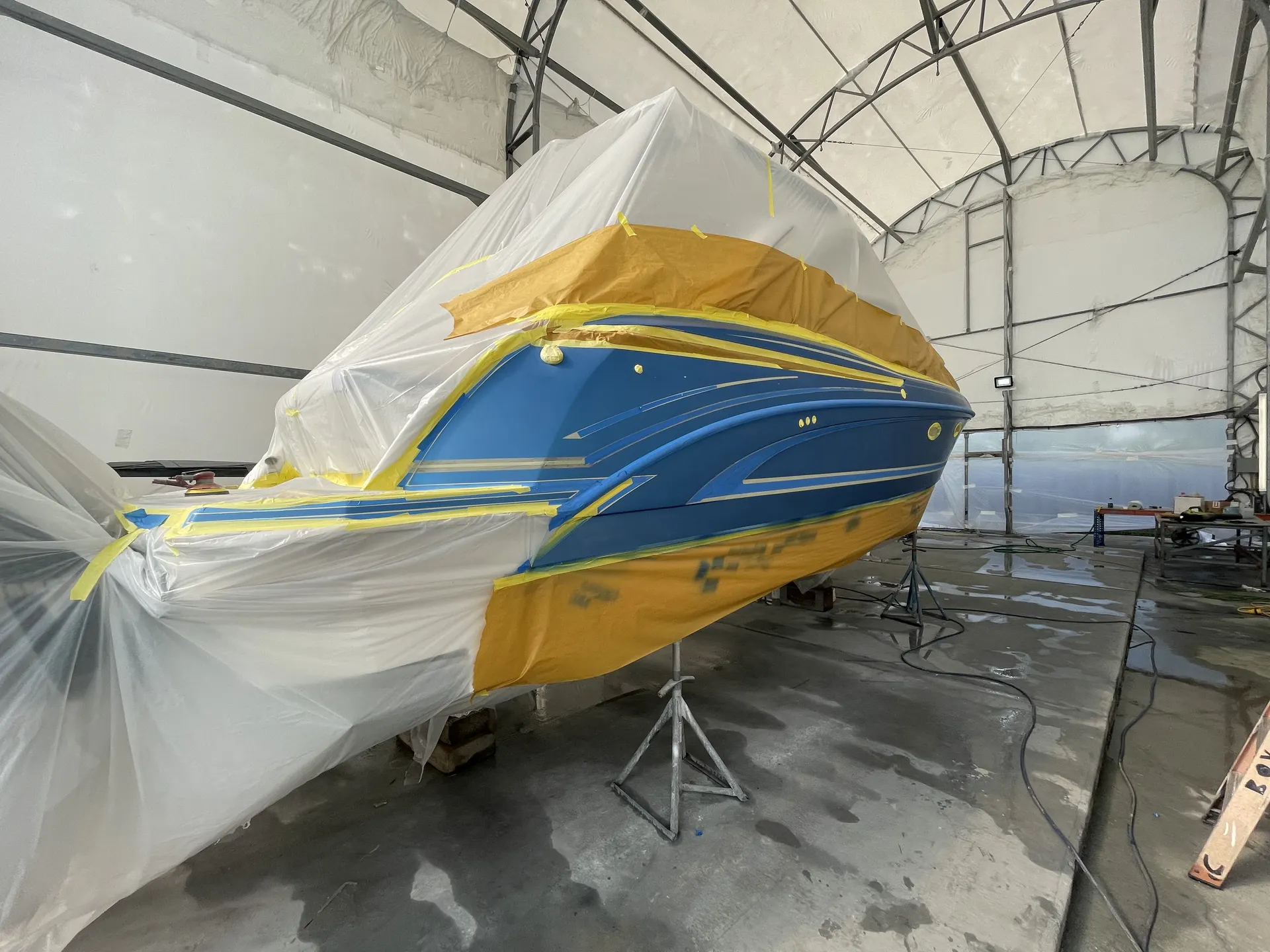 Mid-hull section of a blue powerboat fully masked for refinishing work