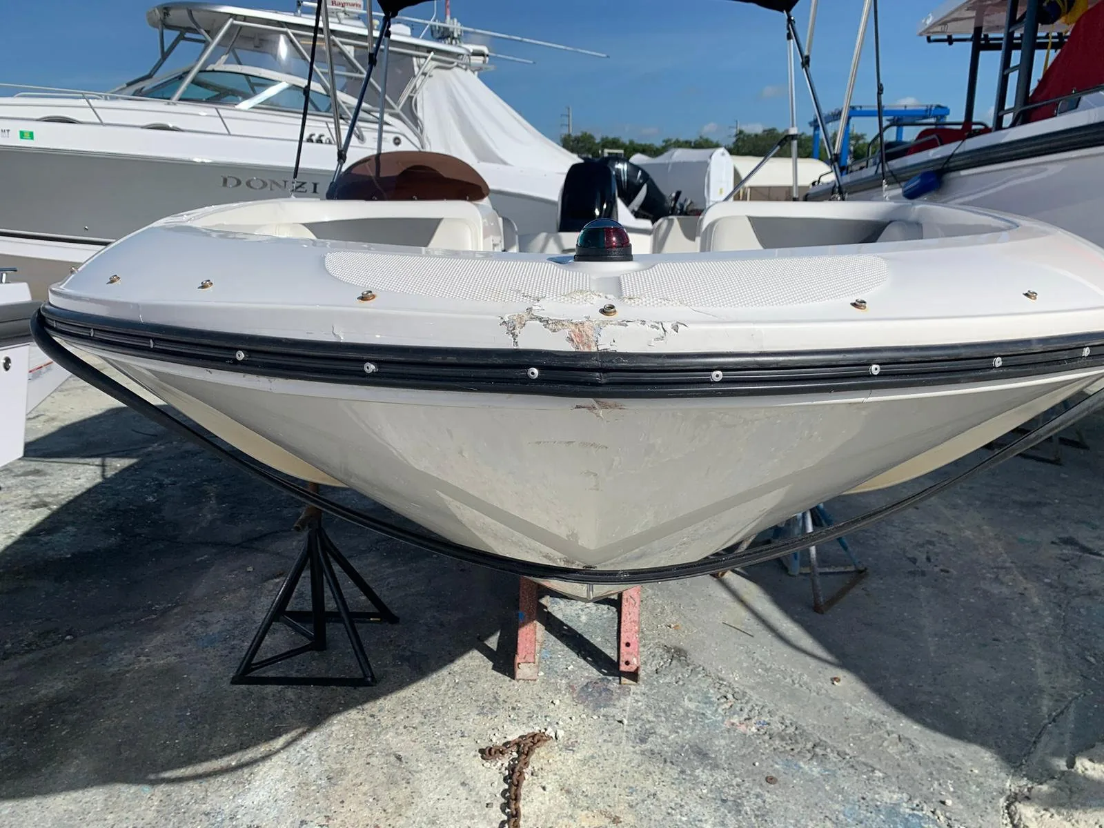 White bow rider with cracked fiberglass and detached rub rail at the bow tip before repair