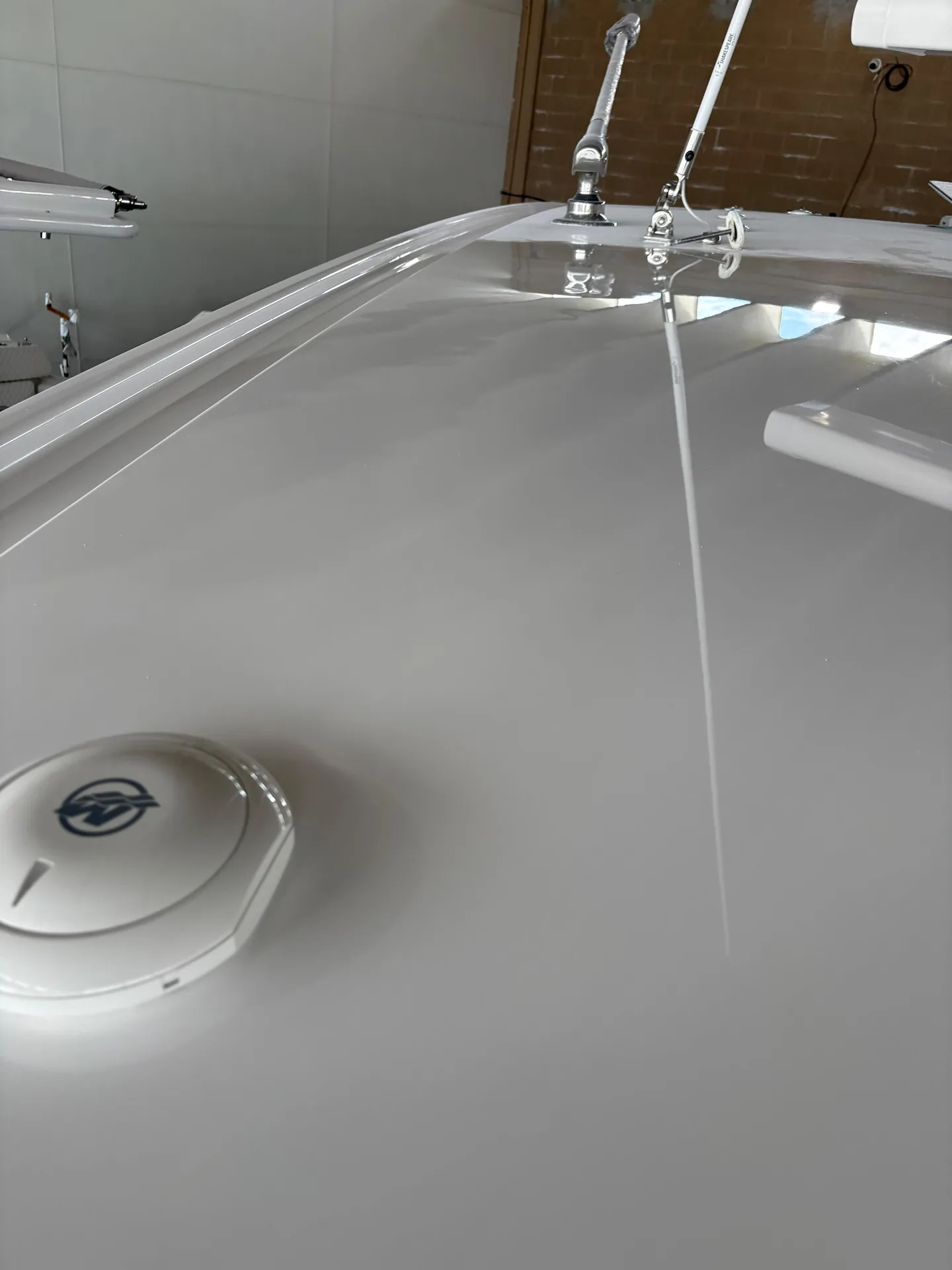 Hardtop surface with a mirror-gloss white finish reflecting overhead workshop lights